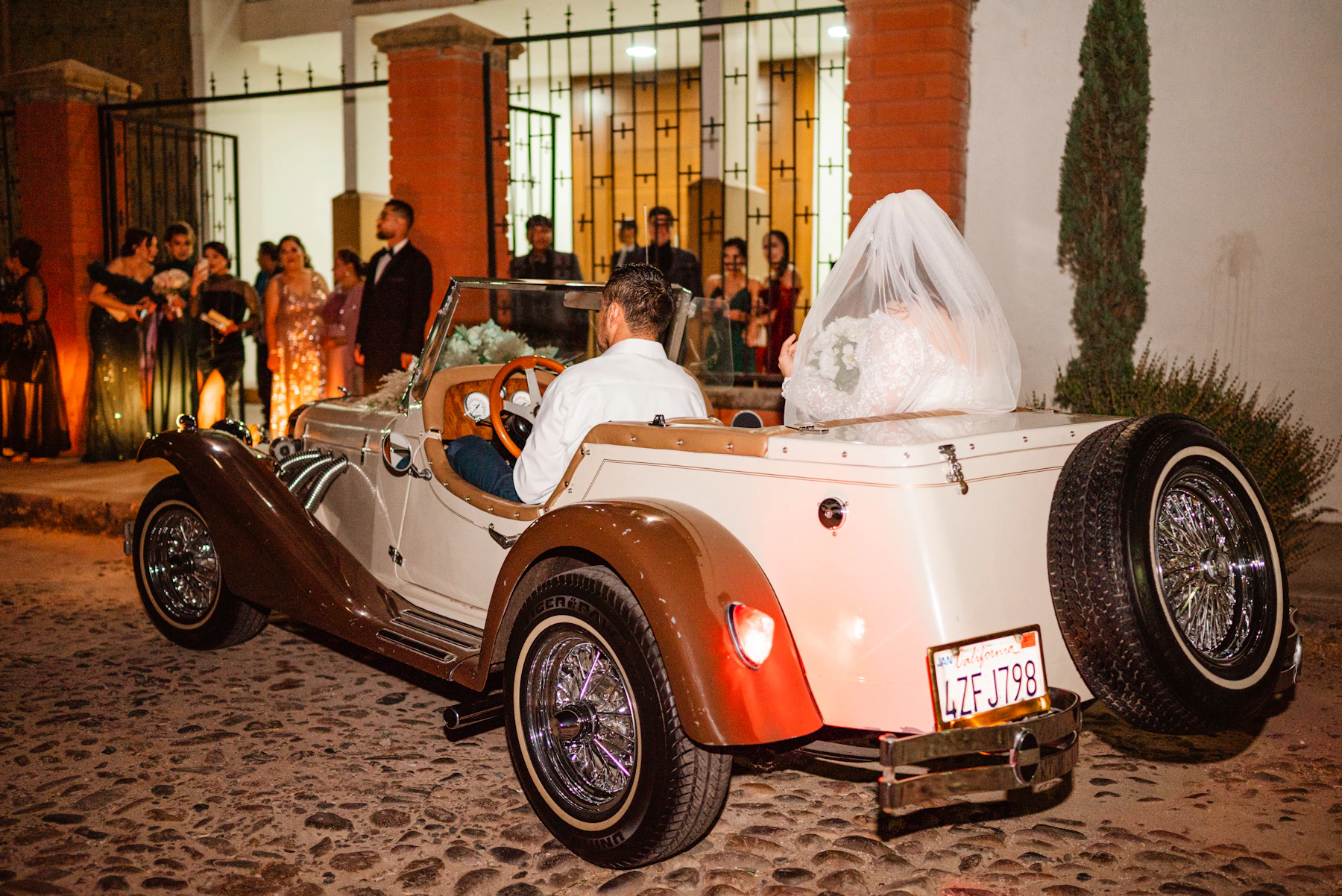 Brautpaar fährt in einem klassischen Hochzeitsauto davon